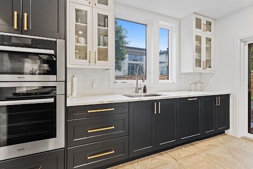 Step-by-step painted kitchen cabinets process — sanding, priming, and spraying a cabinet door.