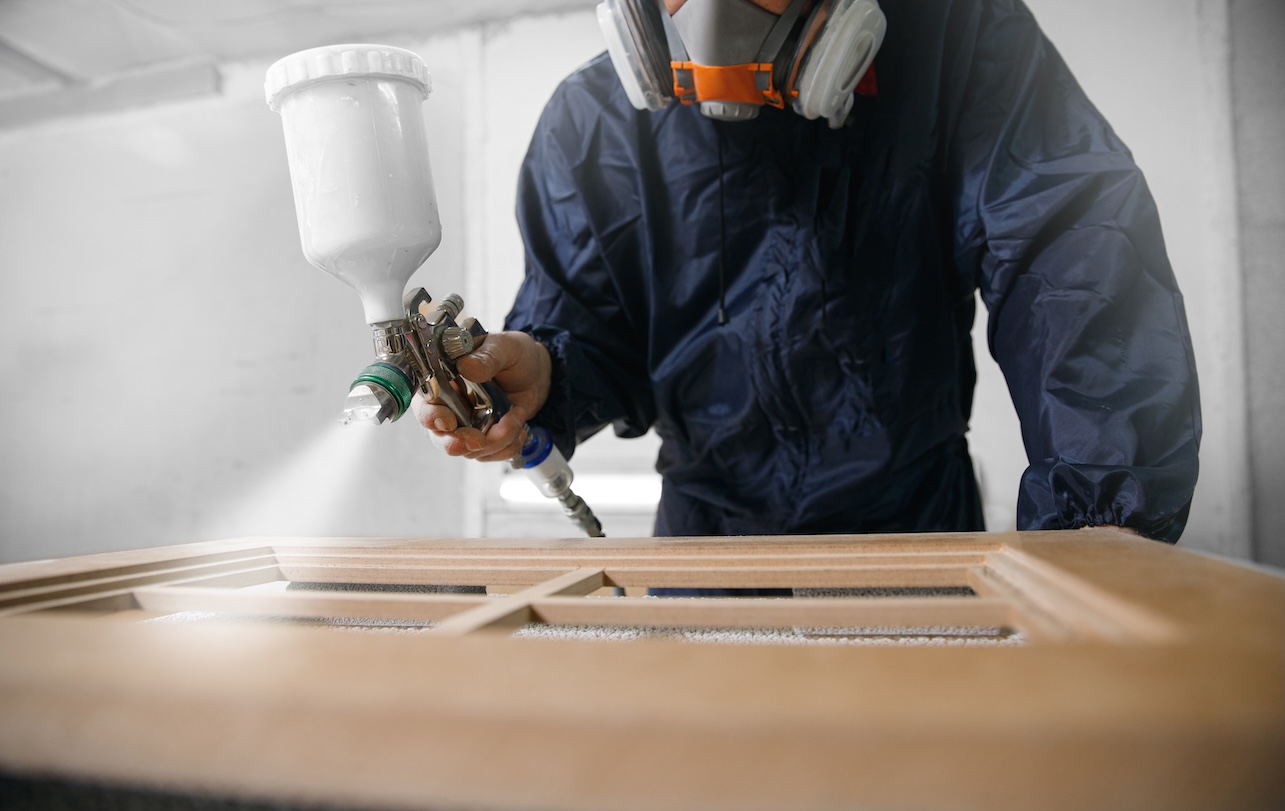 man spray painting kitchen cabinets